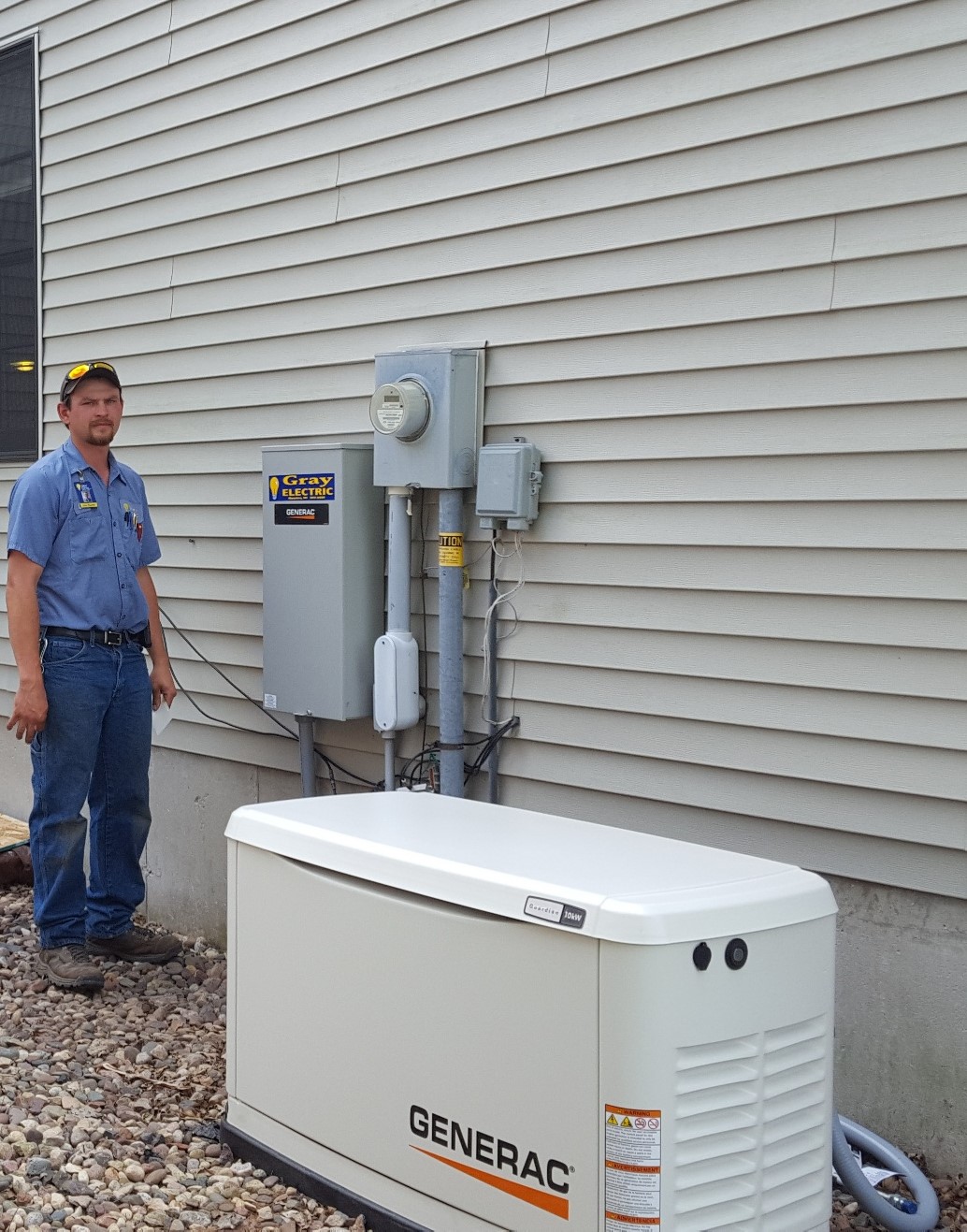A Gray Electric technician beside a completed Generac generator installation