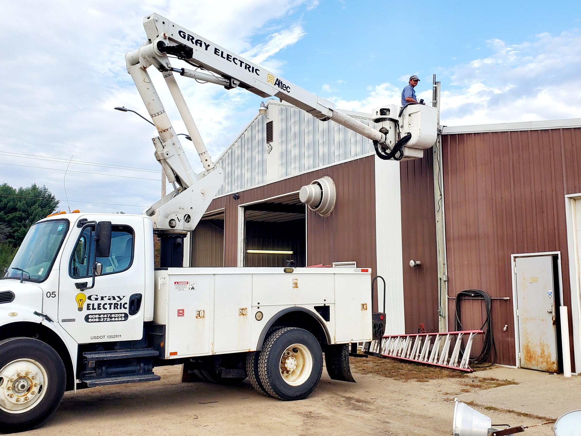 A Gray Electric bucket truck servicing a commercial building exterior
