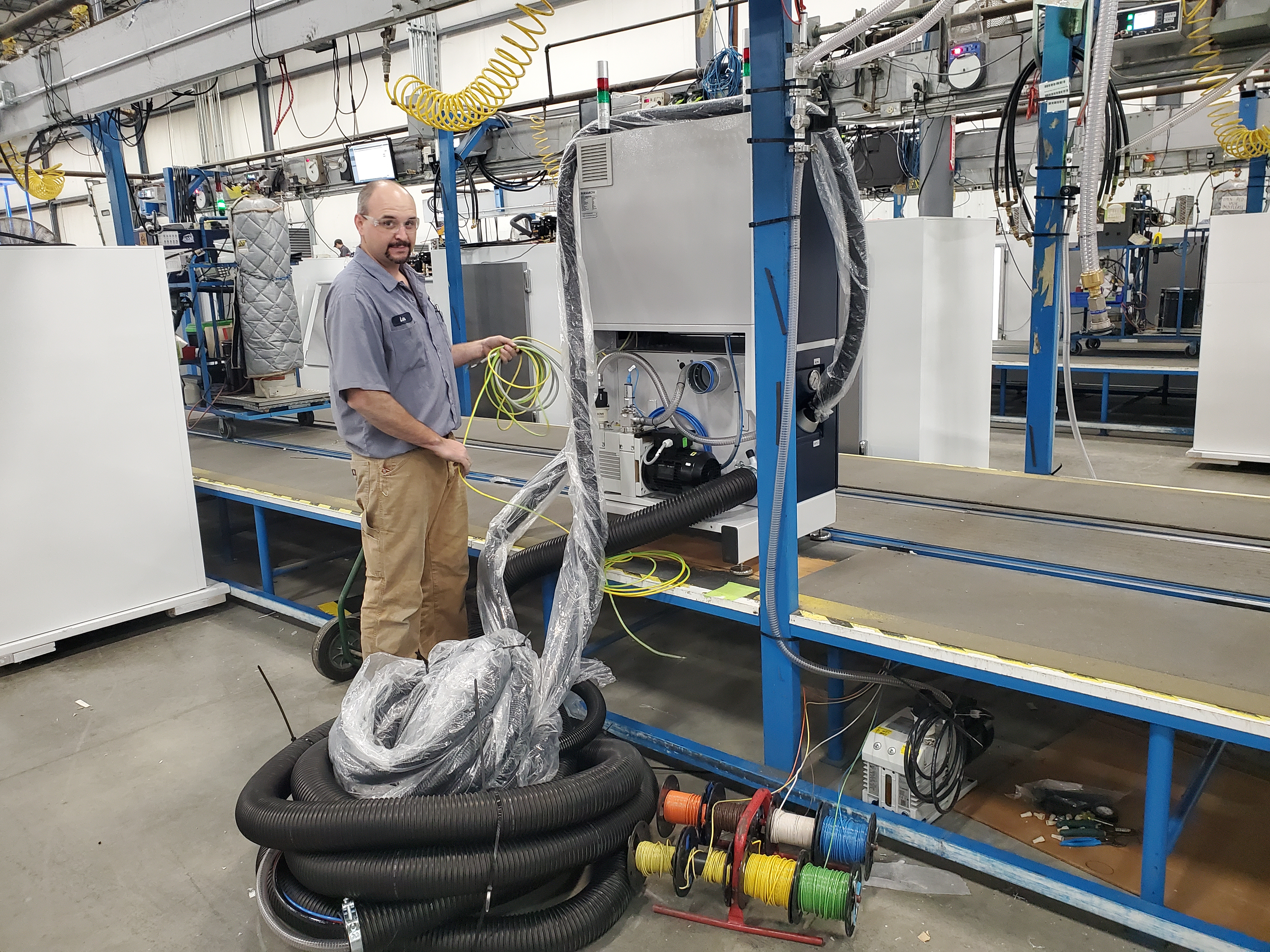 A Gray Electric electrician running conduit and wire on an industrial plant floor